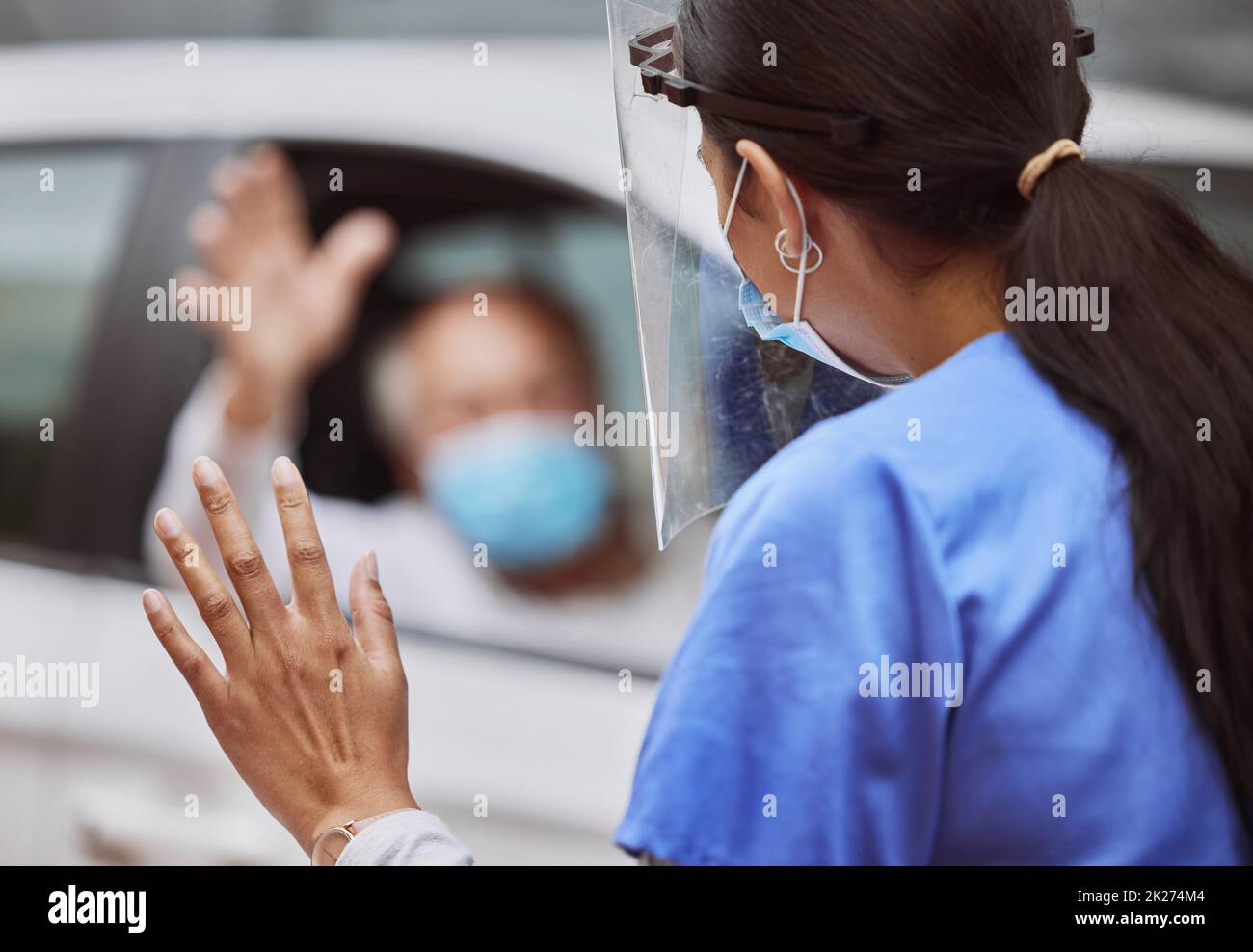 Bis bald. Aufnahme eines nicht erkennbaren Arztes, der auf einer Fahrt durch die Impfstelle einen Patienten anwinkt. Stockfoto