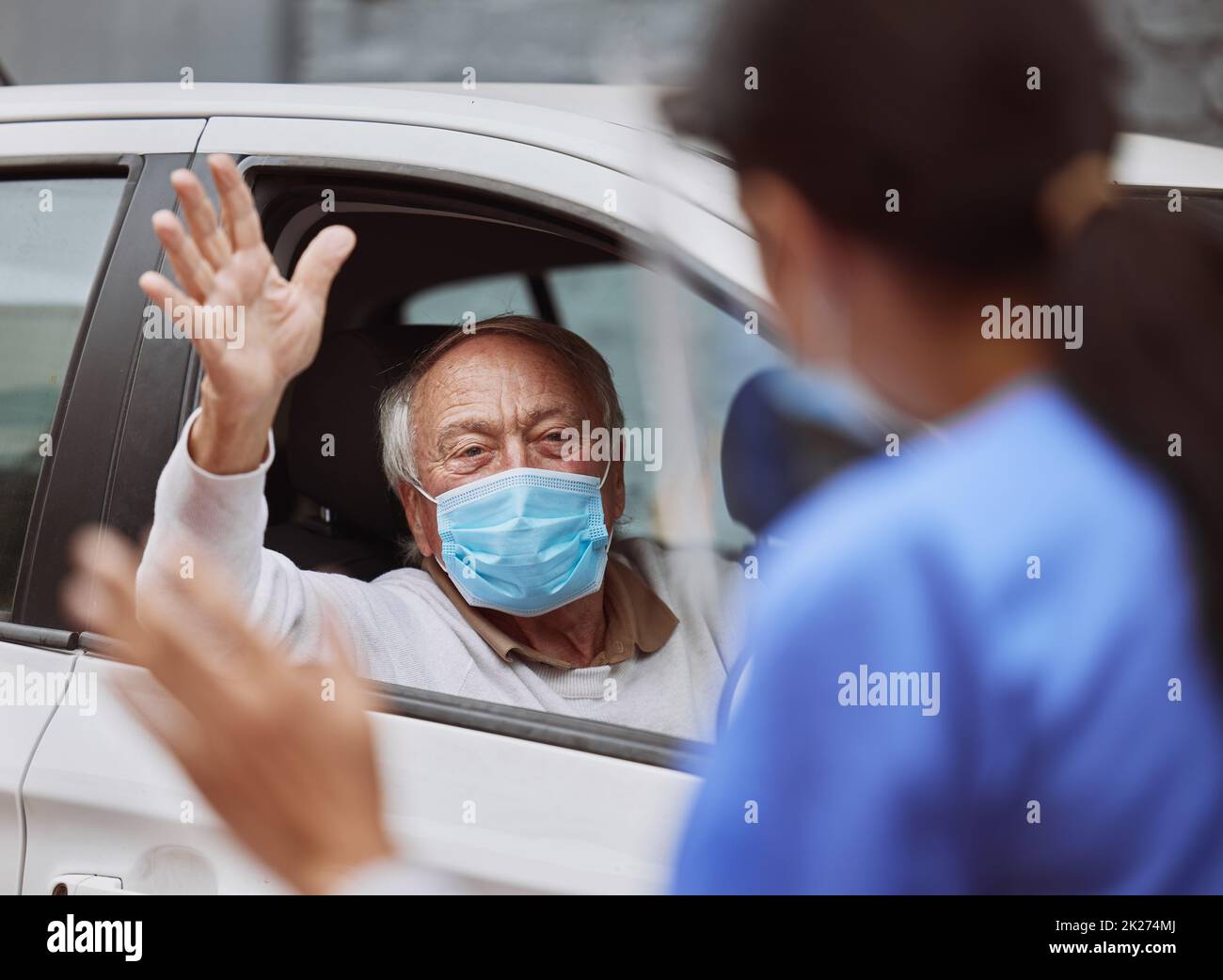 Vielen Dank für Ihre Unterstützung. Aufnahme eines medizinischen Mitarbeiters, der bei einer Fahrt durch die Impfstelle einen Patienten anwinkt. Stockfoto