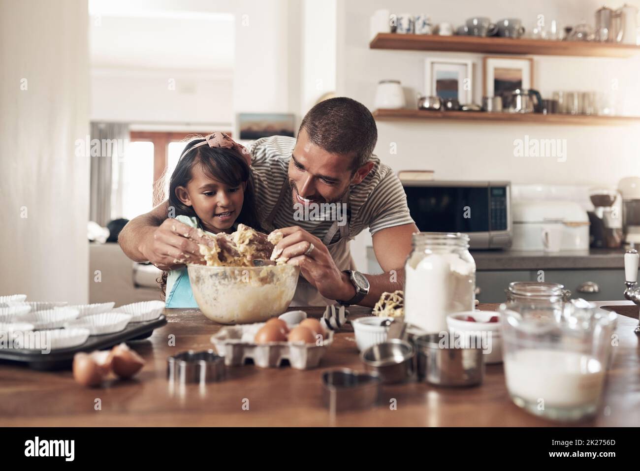 Die Liebe zur Familie ist chaotisch. Aufnahme eines Vaters, der seiner Tochter beibringt, wie man zu Hause in der Küche backen kann. Stockfoto