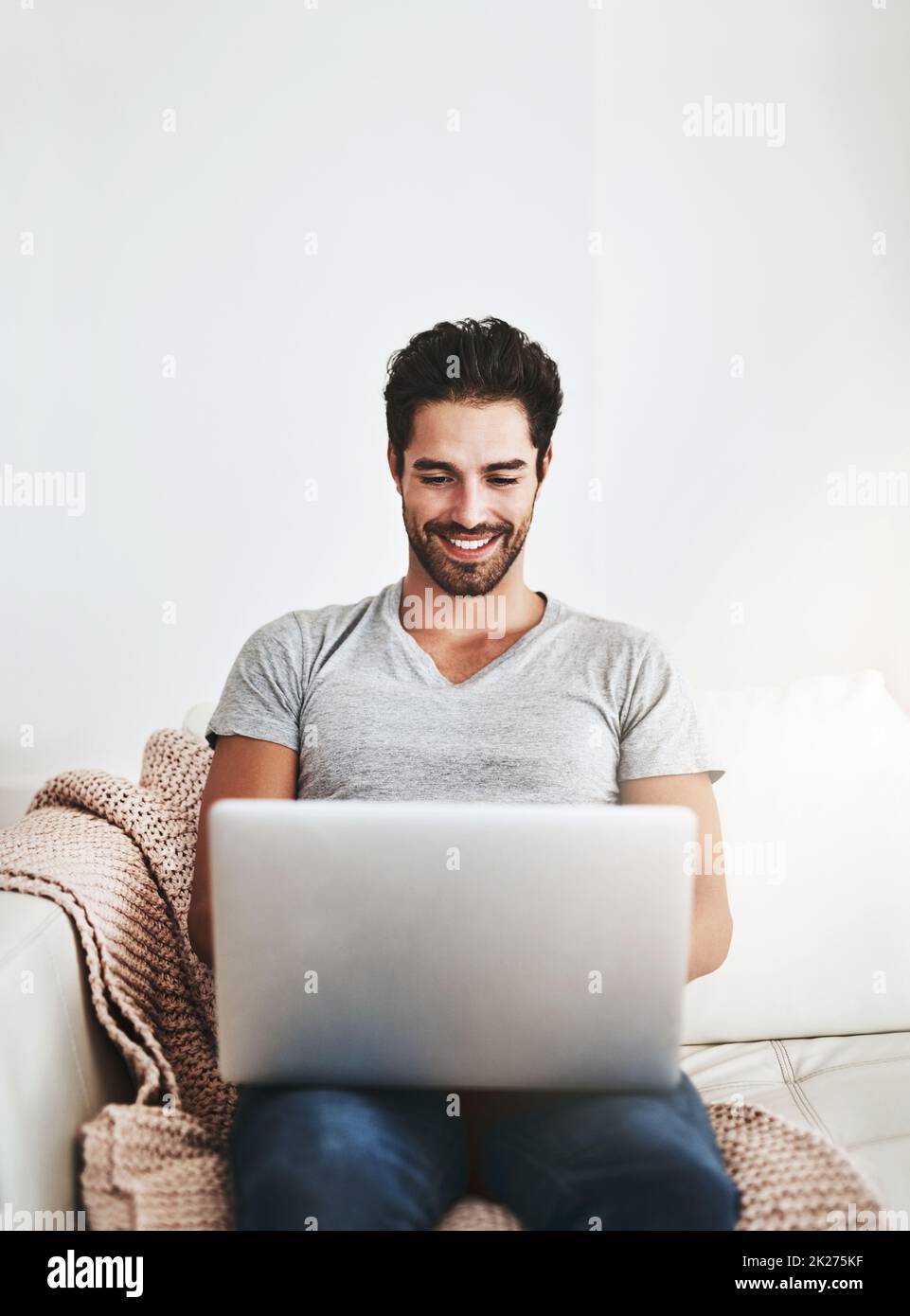 Auf die bequemste Art und Weise verbunden. Aufnahme eines jungen Mannes, der zu Hause drahtlose Technologie auf dem Sofa verwendet. Stockfoto