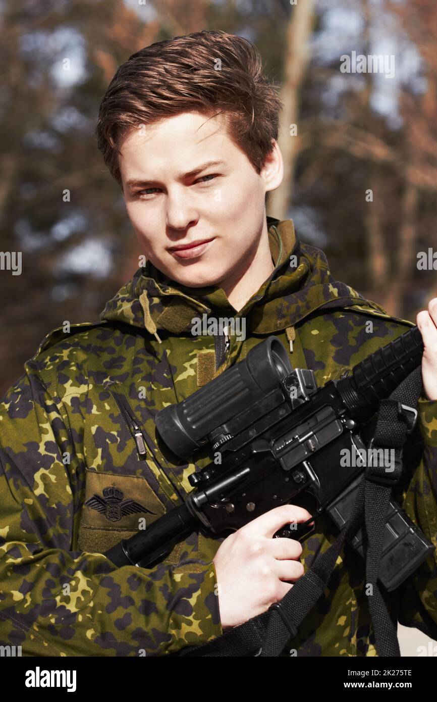 Stolz sein Land beschützen. Ein junger Soldat, der mit einem Gewehr steht. Stockfoto