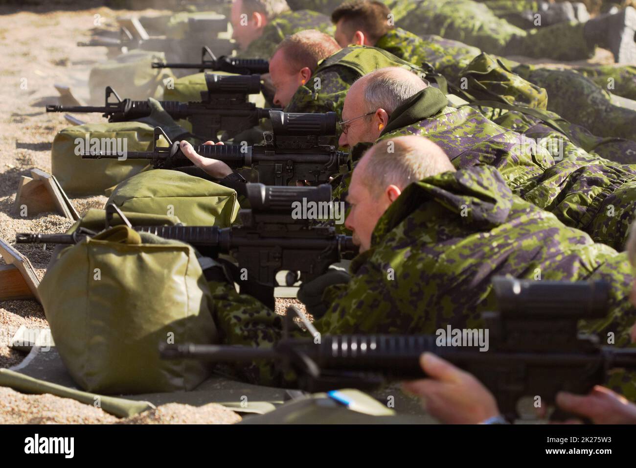 Training für den Krieg. Schuss einer Gruppe von Soldaten, die ihre Gewehre anvisieren, während sie auf dem Boden liegen. Stockfoto