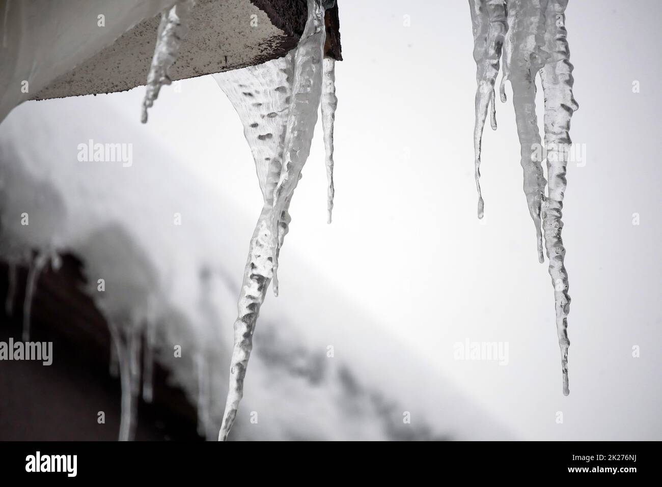 Eiszapfen auf dem Dach, es schneit, es ist ein harter Winter Stockfoto