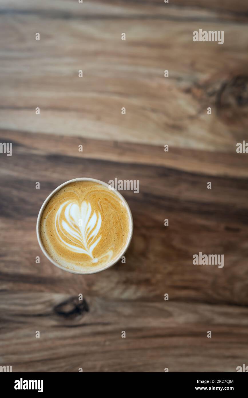 Cappuccino-Kaffee mit wunderschönem Muster auf Schaum in Eco Craft-Glas auf dem Tisch beliebtes Kaffeetassenkonzept. Blick von oben. Stockfoto