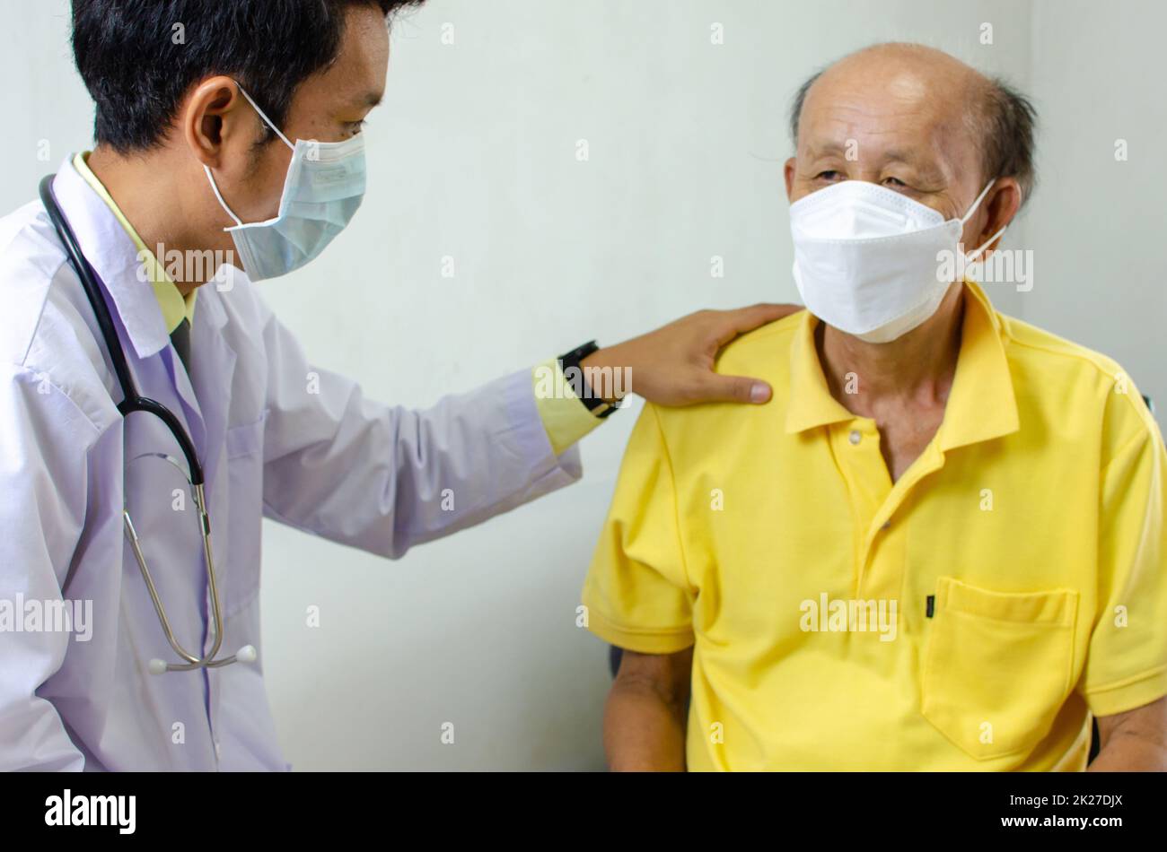 Der Arzt hielt seine Schulter und sprach mit einem älteren Mann, der krank war, um ihn zu ermutigen. Stockfoto