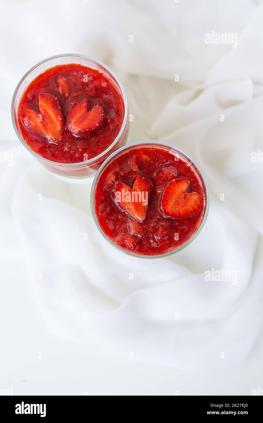 Erdbeer-Chiasamen-Pudding in einer Tasse zum Frühstück und Erdbeeren in Herzform. Februar 14, St. Valentinstag. Stockfoto