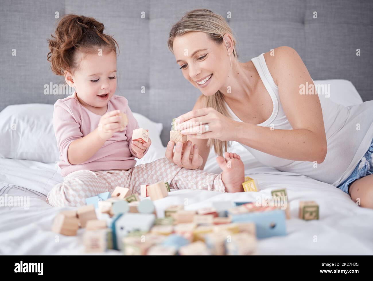 Bett, glückliche Mutter und Baby mit Spielzeug spielen zusammen mit Alphabet Bildung Bausteine im Schlafzimmer zu Hause. Familienliebe, Kinderentwicklung und Spaß für Stockfoto