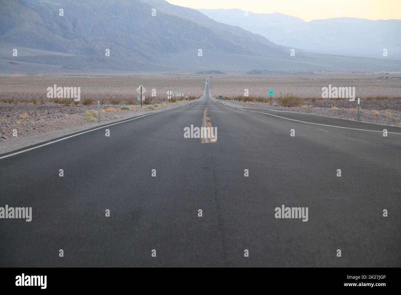 Die nie endende Straße während der Abenddämmerung eines Sonnenuntergangs in der Death Valley Wüste Stockfoto