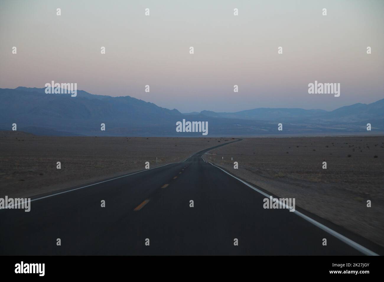 Die nie endende Straße während der Abenddämmerung eines Sonnenuntergangs in der Death Valley Wüste Stockfoto