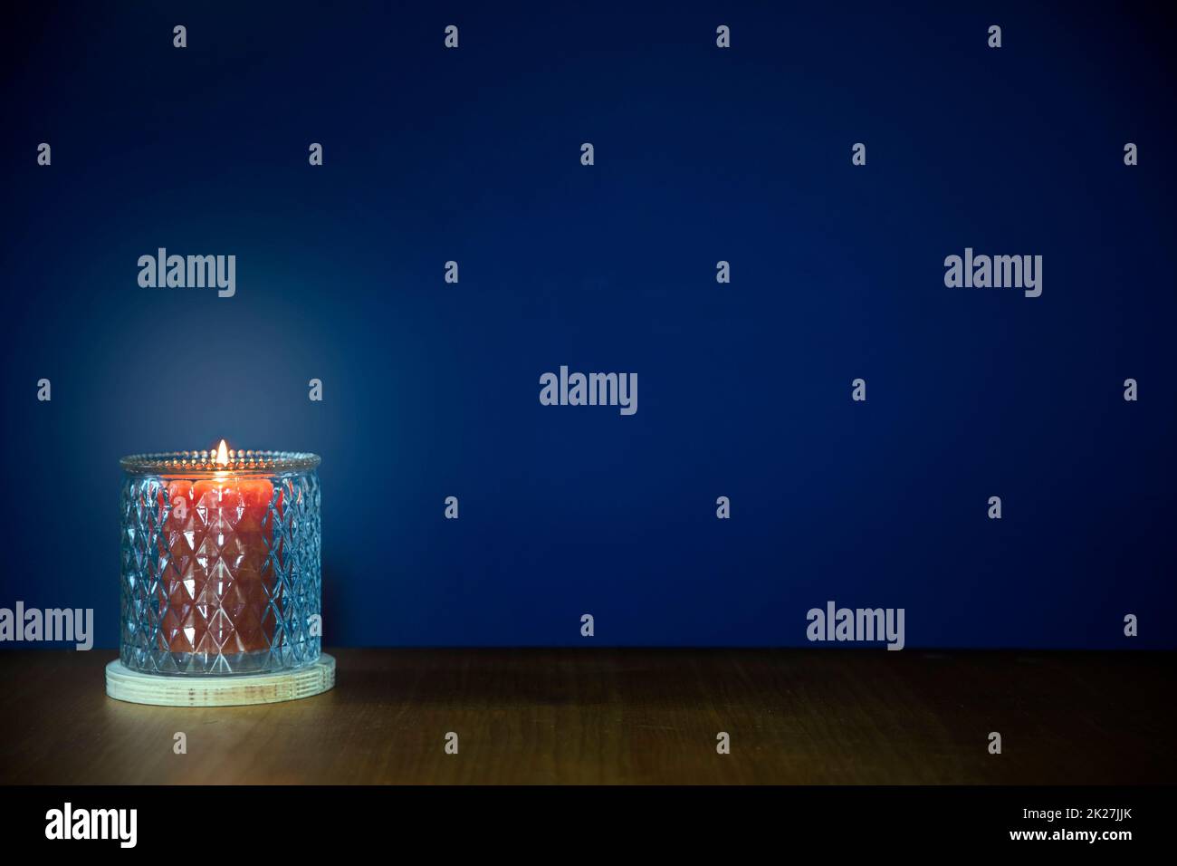 Brennende Kerzen auf Holztisch vor dunkelblauem Hintergrund mit Kopierraum. Stilvolle Wohndekoration Stockfoto