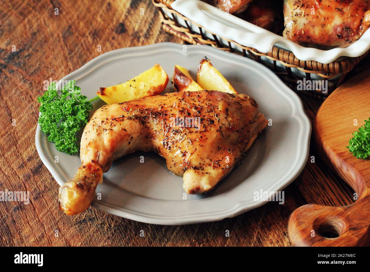 Gegrilltes Hähnchenschenkel mit Kartoffeln zum Garnieren. Holzhintergrund. Stockfoto