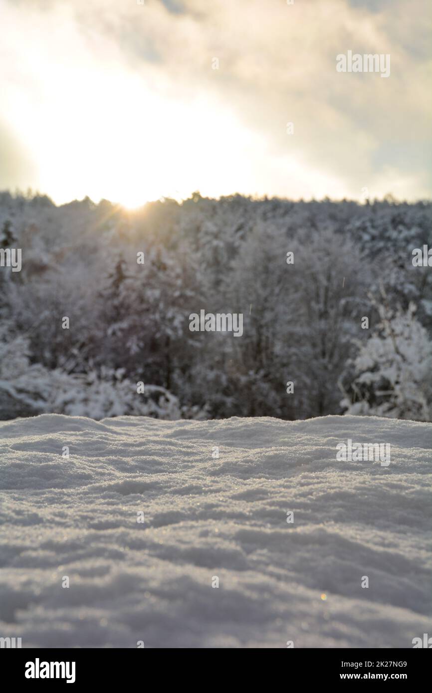 Tiefer Schnee mit Sonnenaufgang hinter den verschwommenen Bäumen Stockfoto