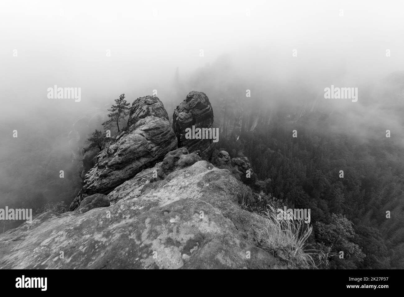 Ein früher bewölkter Morgen in den Bergen. Schrammsteine - eine Gruppe von Felsen ist eine lange, weit gestreckte, sehr zerklüftete Gruppe in den Elbsandsteinbergen in der sächsischen Schweiz in der DDR. Schwarz auf Weiß. Stockfoto