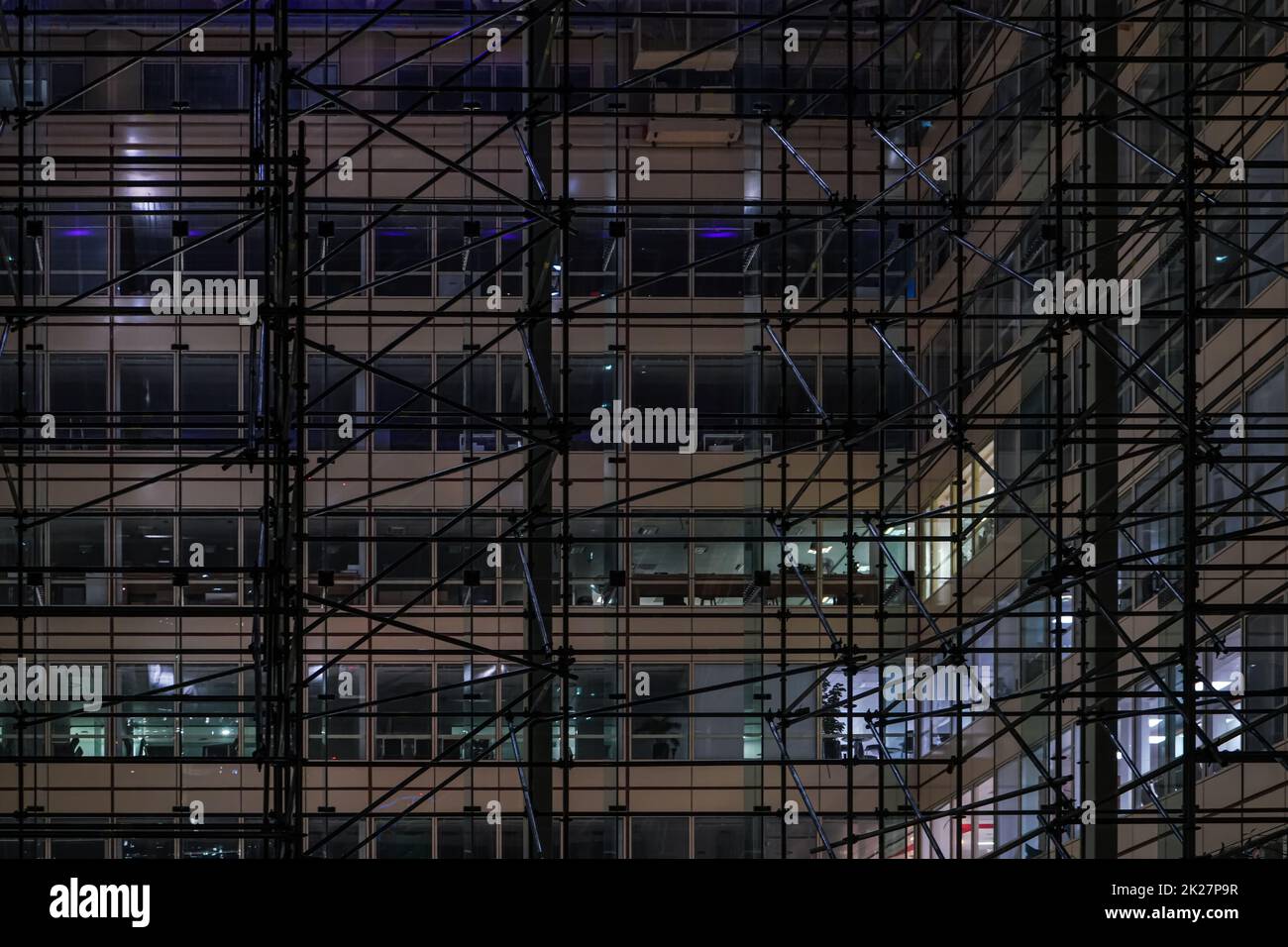Eisengerüstkonstruktion rund um das moderne Bürogebäude aus Stahl und Glas in der Nacht Stockfoto