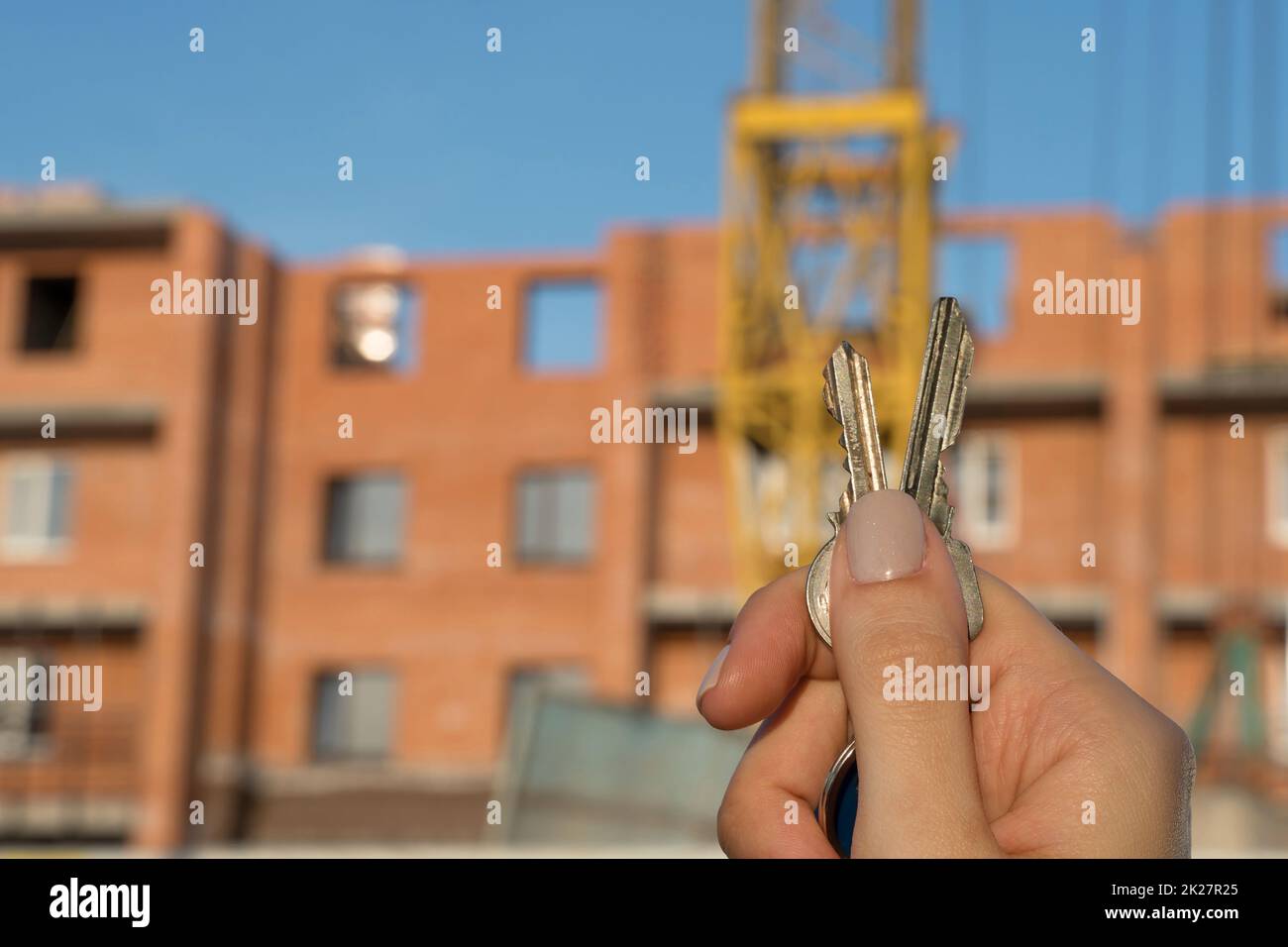 Bau eines neuen Gebäudes oder eines neuen Wolkenkratzers.Baustelle.Hände halten die Schlüssel für ein neues Haus.Hypothek für den Bau von Wohnungen.Immobilien und Grundstücke kaufen.Schuldverschreibungen Stockfoto