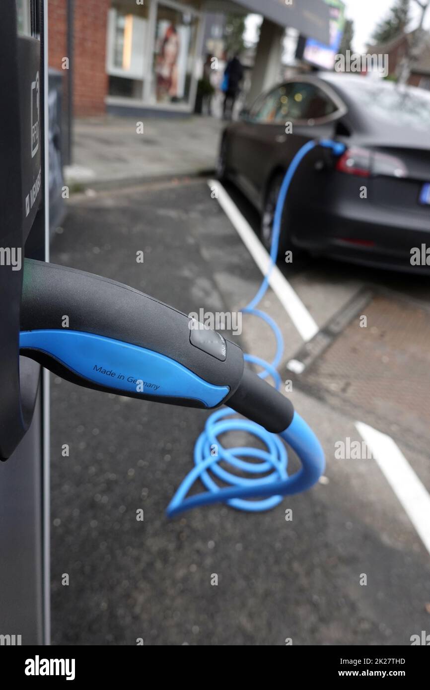 Auto an einer E-Tankstelle mit blauem Ladekabel Stockfoto