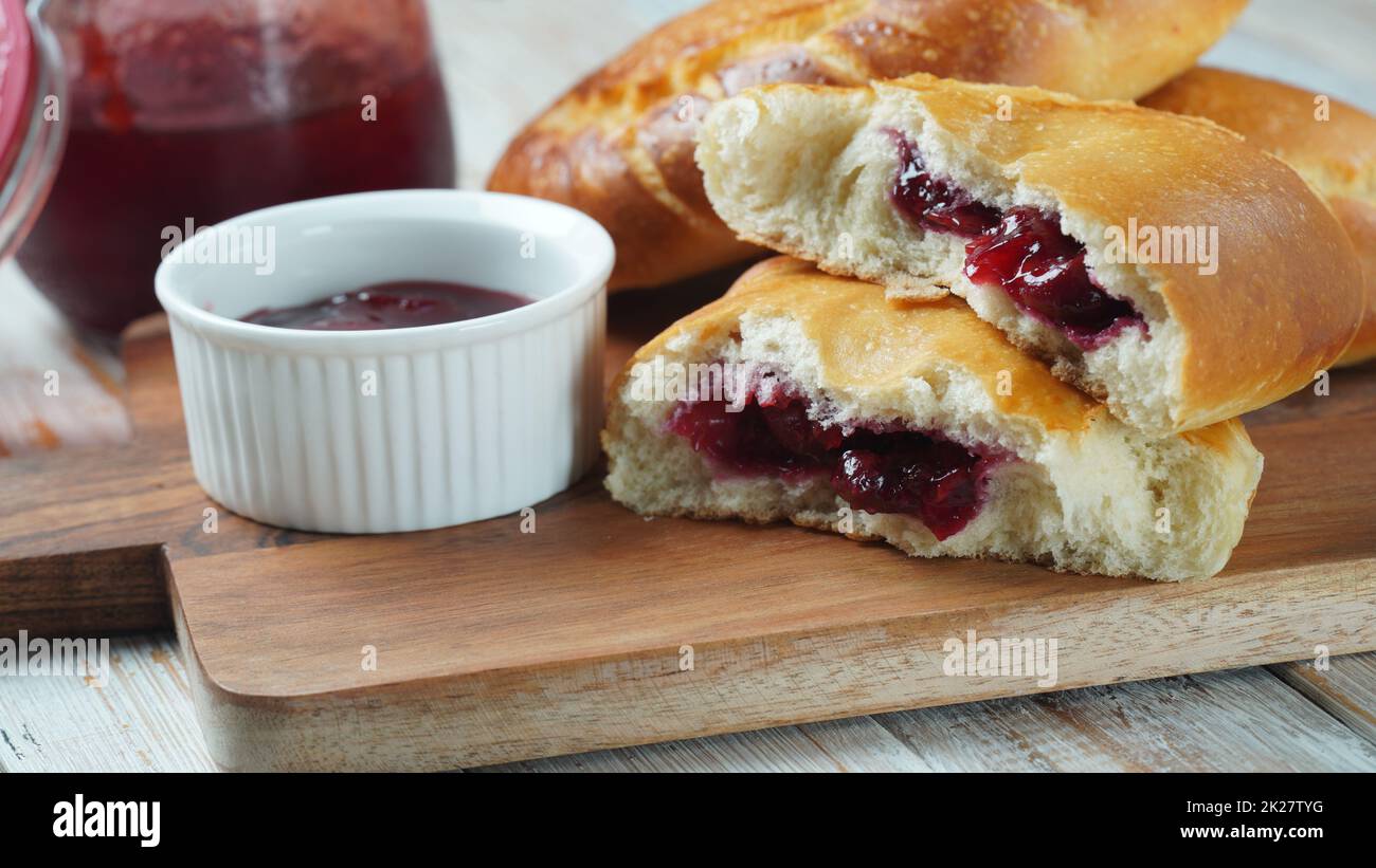 Cherry Pies gefüllt mit Beeren Kirsche, Schüssel mit Kirschmarmelade. Hausgemachte süße Kuchen aus Hefeteig frisch im Ofen gebacken Stockfoto