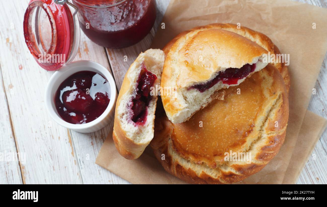 Cherry Pies gefüllt mit Beeren Kirsche, Schüssel mit Kirschmarmelade. Hausgemachte süße Kuchen aus Hefeteig frisch im Ofen gebacken Stockfoto