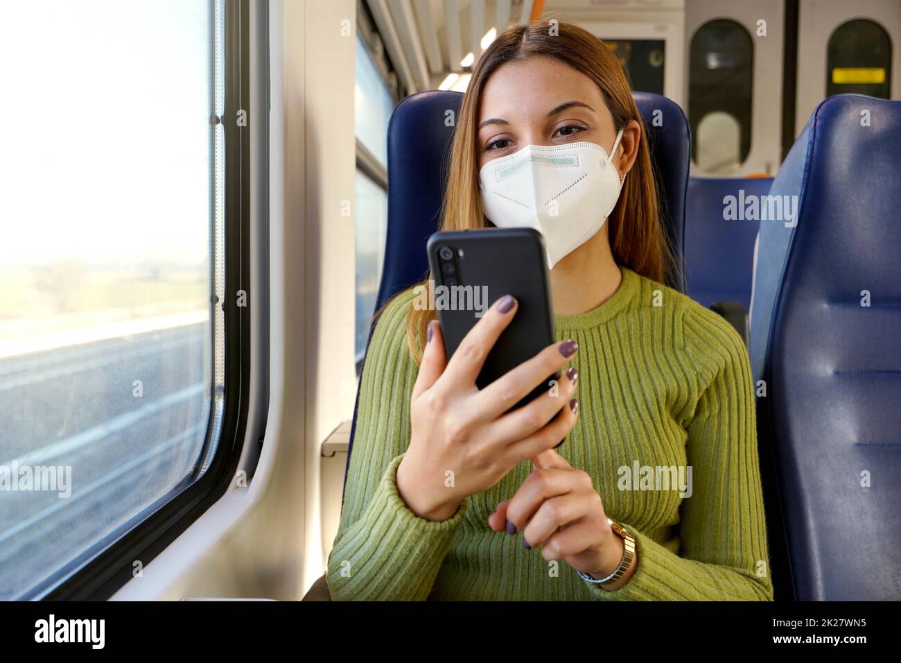 Trainieren Sie den Passagier mit der Smartphone-App während der Fahrt zur Arbeit und tragen Sie eine Gesichtsmaske Stockfoto