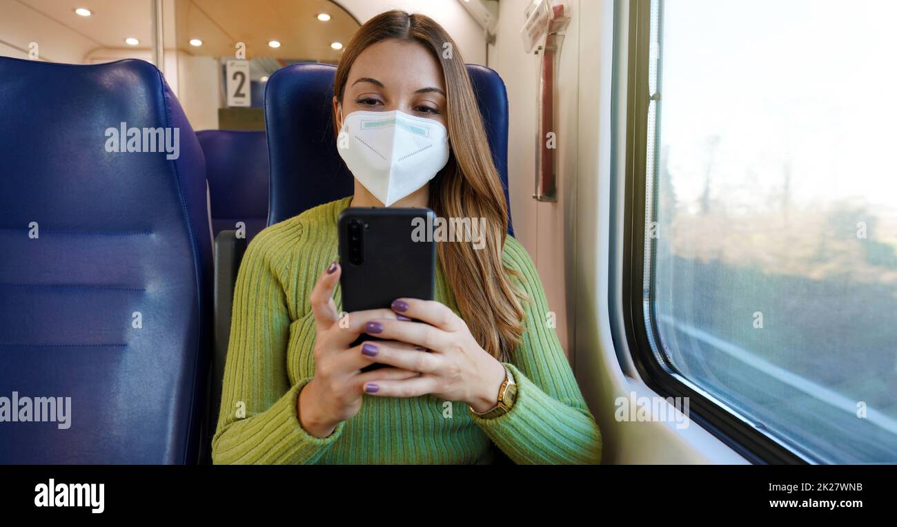 Entspannter Zugpassagier mit Smartphone-App während der Fahrt auf dem Weg zur Arbeit mit Gesichtsschutzmaske. Panorama-Banner über den Lebensstil von Menschen beim Pendeln nach der Arbeit. Stockfoto