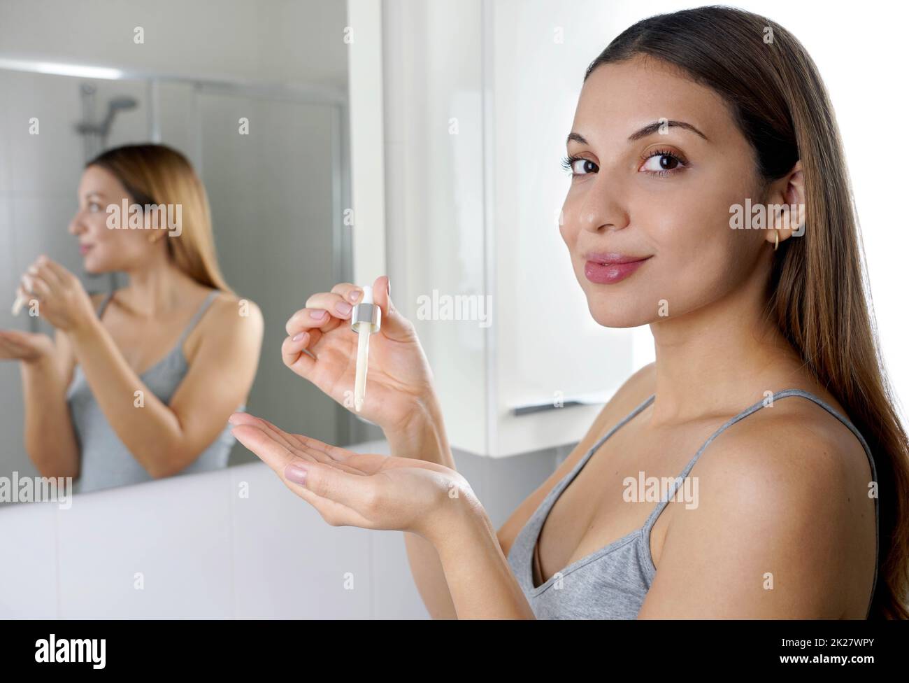 Hautpflegeprogramm. Schöne Frau, die die Kamera mit einer Pipette in der Hand mit Serum-feuchtigkeitsspendenden Anti-Aging-Antioxidans betrachtet. Stockfoto