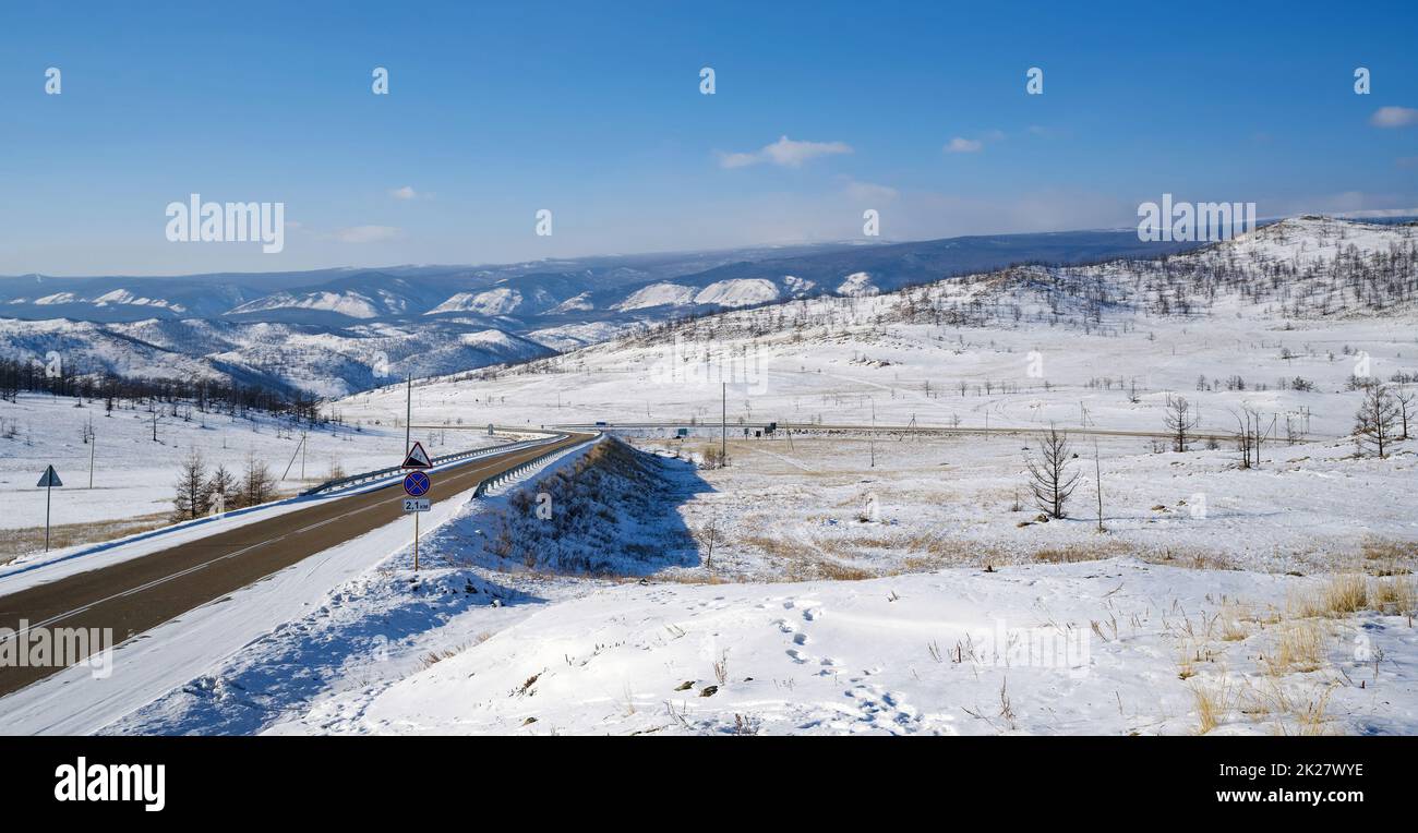 Die Morgenstimmung auf den schneebedeckten Bergen der Kurkutsky Bay. Zwei Straßen durchschneiden die Berge. Baikalsee, Russland. Stockfoto