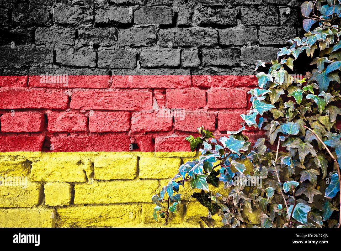 Deutsche Grunge-Fahne an der Ziegelwand mit Efeu-Pflanze Stockfoto