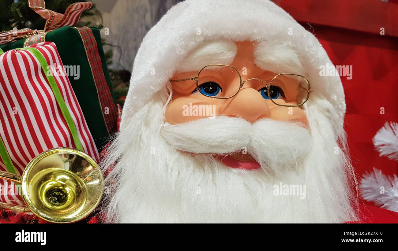 Das Foto einer fröhlichen Spielzeugpuppe Weihnachtsmann mit einer Geschenktüte symbolisiert die Ankunft von Weihnachten und Neujahr. Festliche Stimmung, Urlaubskonzept. Stockfoto