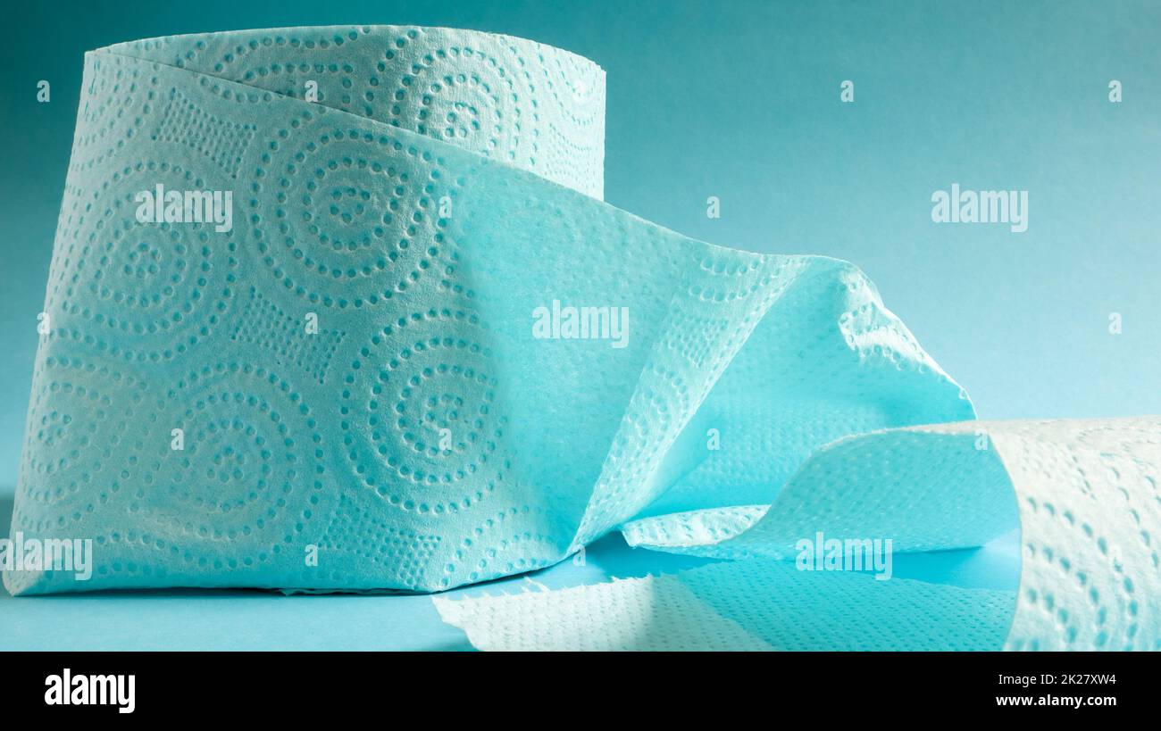 Blaue Rolle mit modernem Toilettenpapier auf blauem Hintergrund. Ein Papierprodukt auf einer Papphülle aus Zellulose für Sanitärzwecke mit Ausschnitten zum einfachen Abreißen. Geprägte Zeichnung Stockfoto