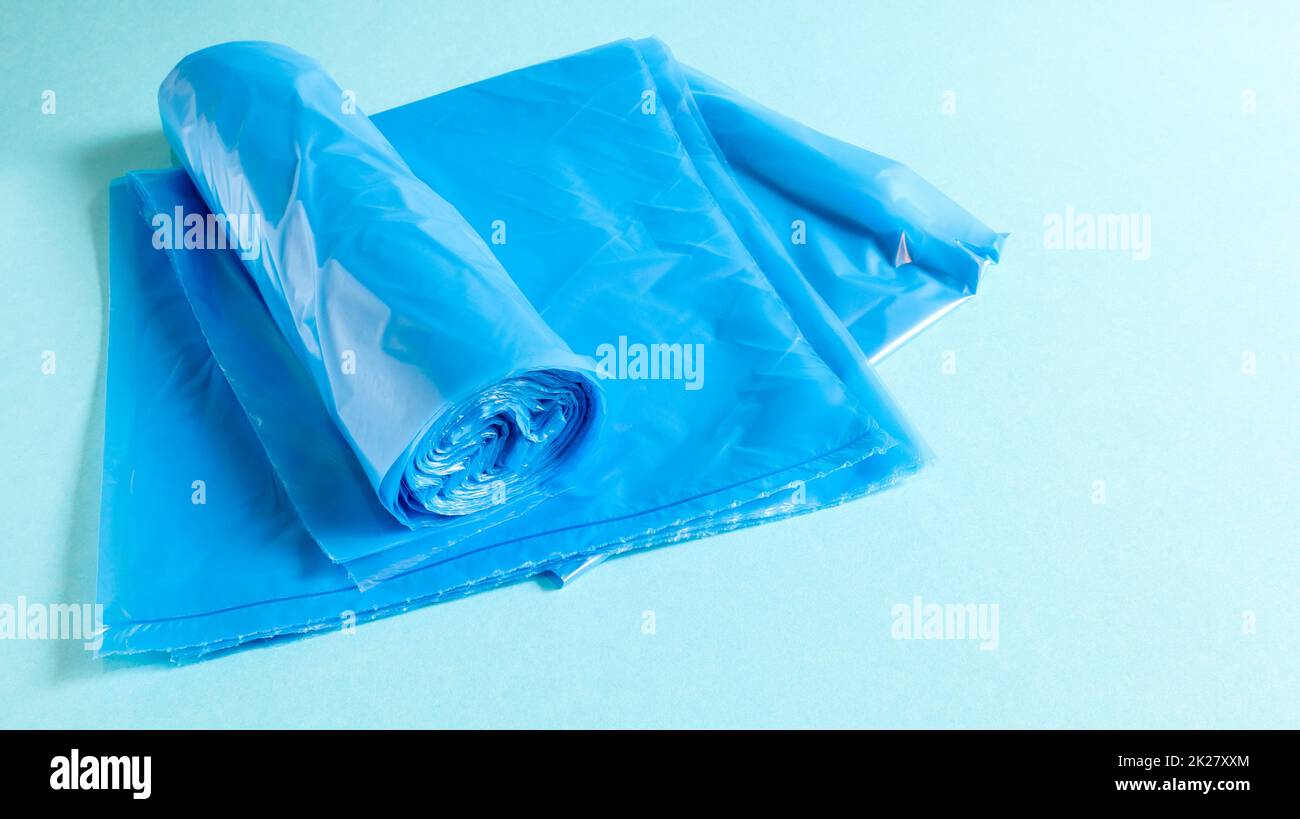 Eine Rolle Plastik-Müllsäcke in Blau auf blauem Hintergrund. Beutel, die für Müll ausgelegt sind, zu Hause verwendet und in verschiedene Müllcontainer gelegt werden. Stockfoto