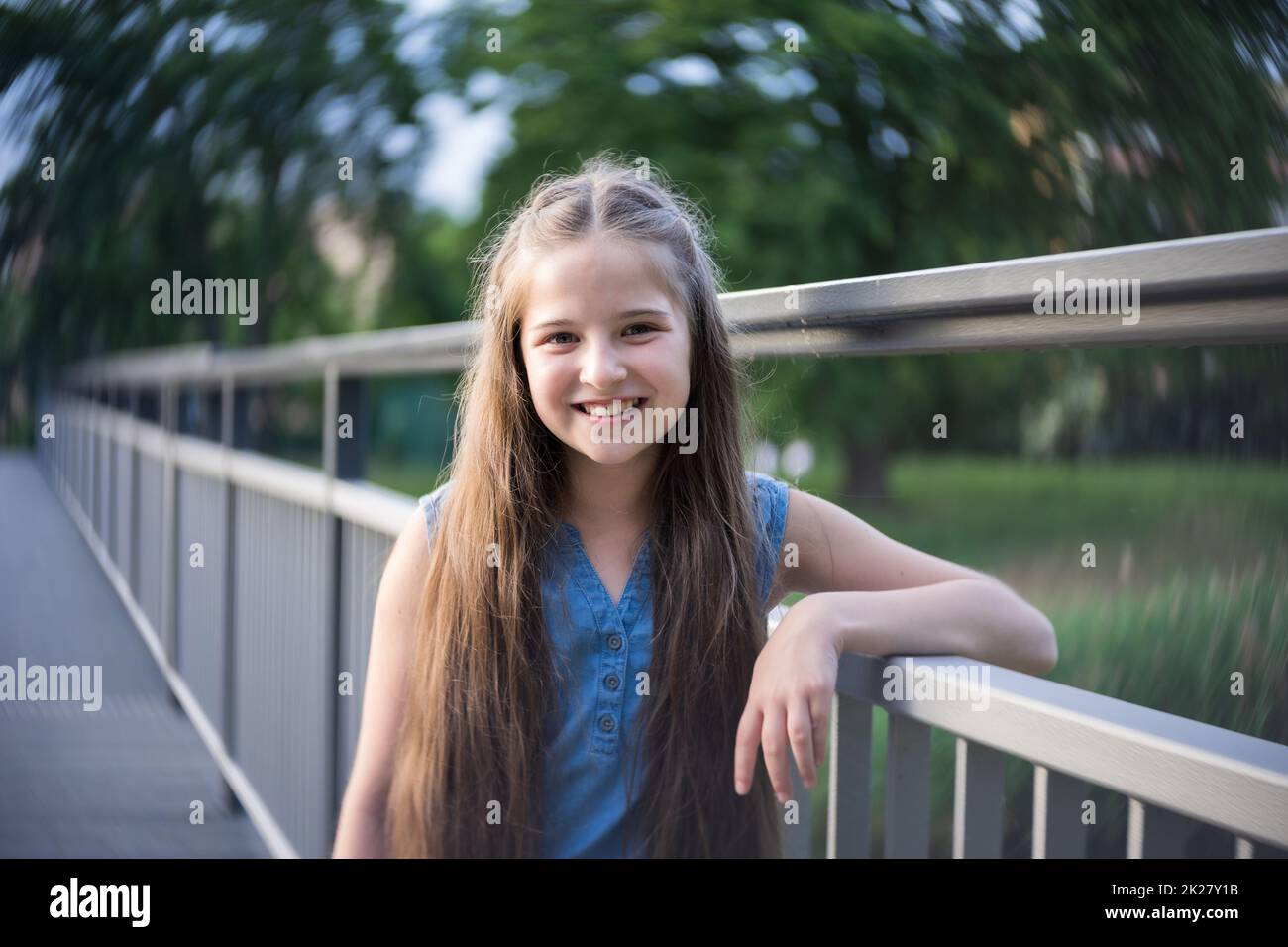 Portrait eines schönen Mädchens mit langen Haaren, das auf einer Brücke steht. Stockfoto