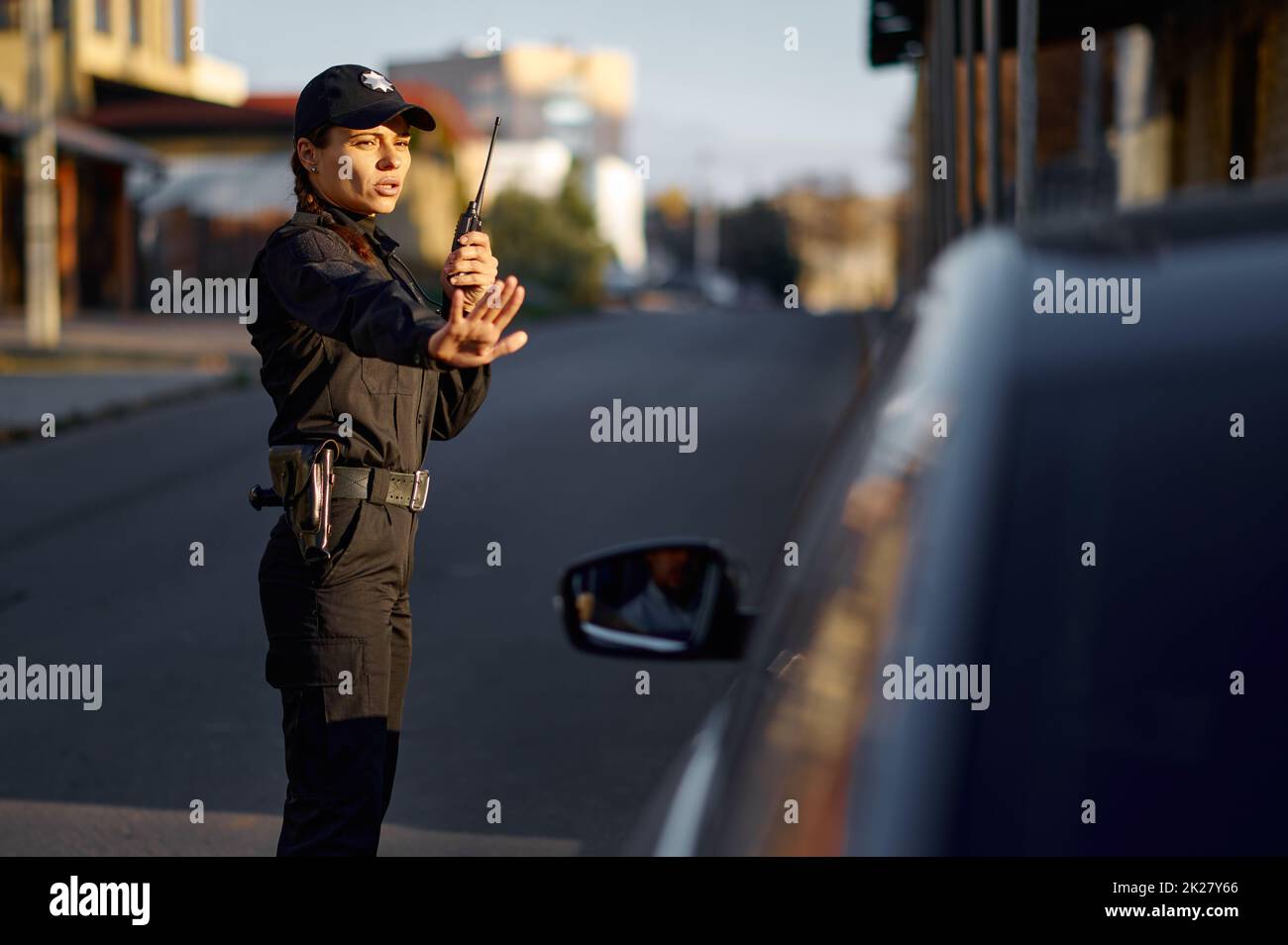 Polizeifrau, die den Straßenverkehr mit Walkie-Talkie kontrolliert Stockfoto