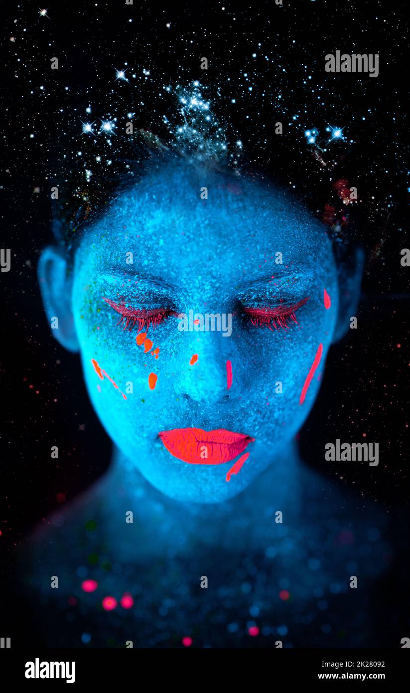 Galaktische Schönheit. Eine junge Frau posiert mit Neonfarbe auf ihrem Gesicht. Stockfoto