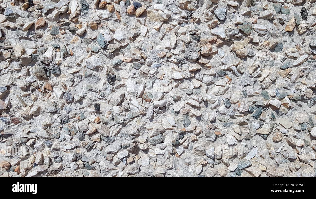 Kieselschutt im Zementhof. Schmutzige, gerissene alte Grunge Vintage hellgrauer Beton und Zementform Struktur Wand- oder Bodenhintergrund mit verwitterter Farbe und Kratzern Stockfoto