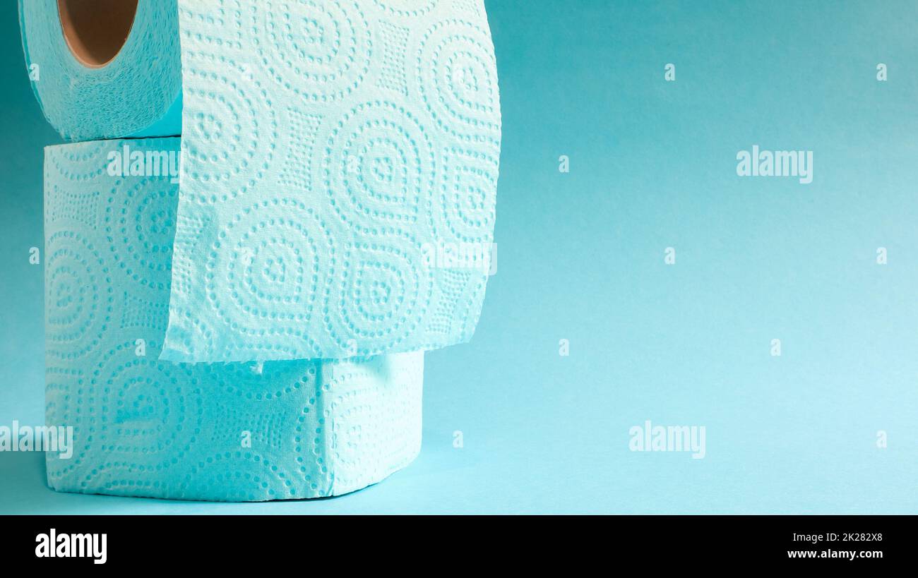 Blaue Rolle mit modernem Toilettenpapier auf blauem Hintergrund. Ein Papierprodukt auf einer Papphülle aus Zellulose für Sanitärzwecke mit Ausschnitten zum einfachen Abreißen. Geprägte Zeichnung. Speicherplatz kopieren. Stockfoto