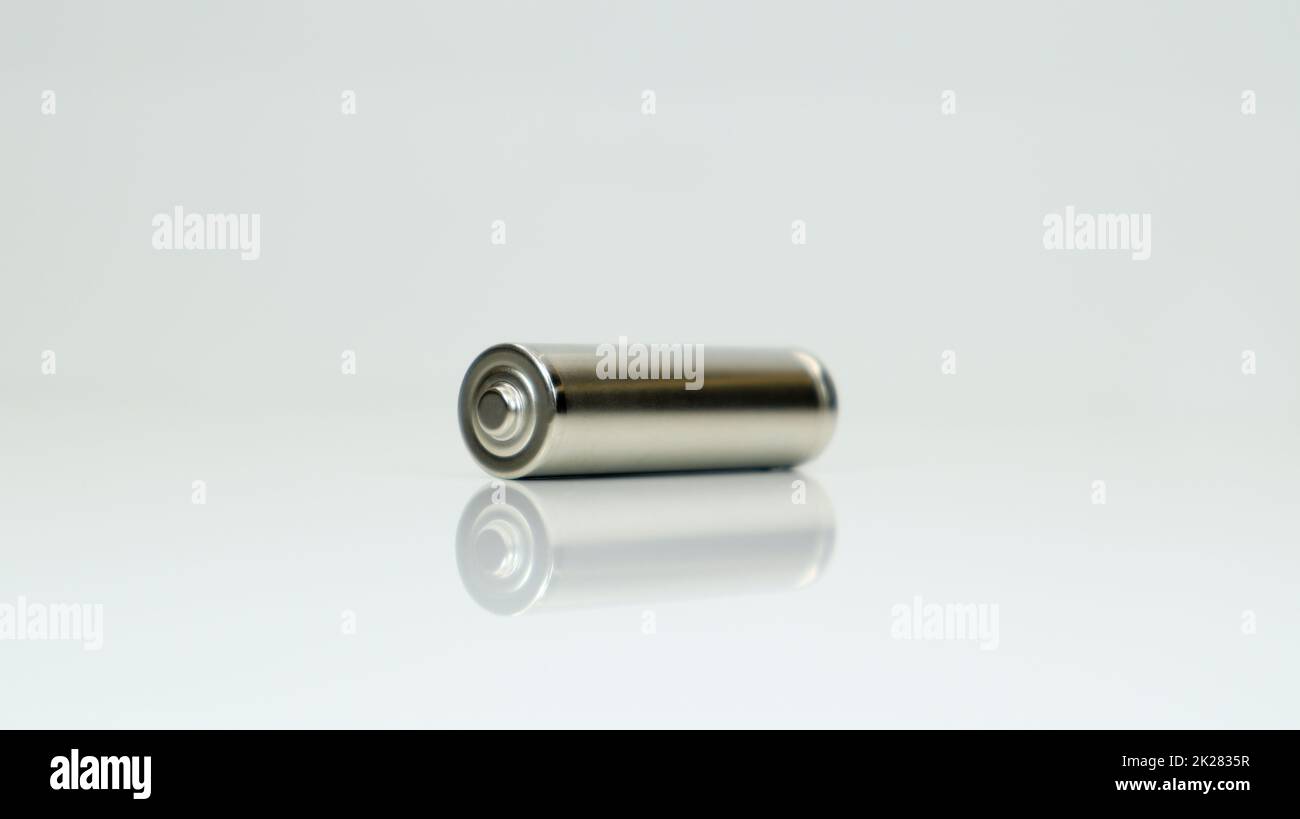 AA-Alkali-Mangan-Batterie auf weißem, glänzendem Hintergrund mit Reflexion. Schließen Sie eine leere Batterie mit Kopierraum. Stockfoto