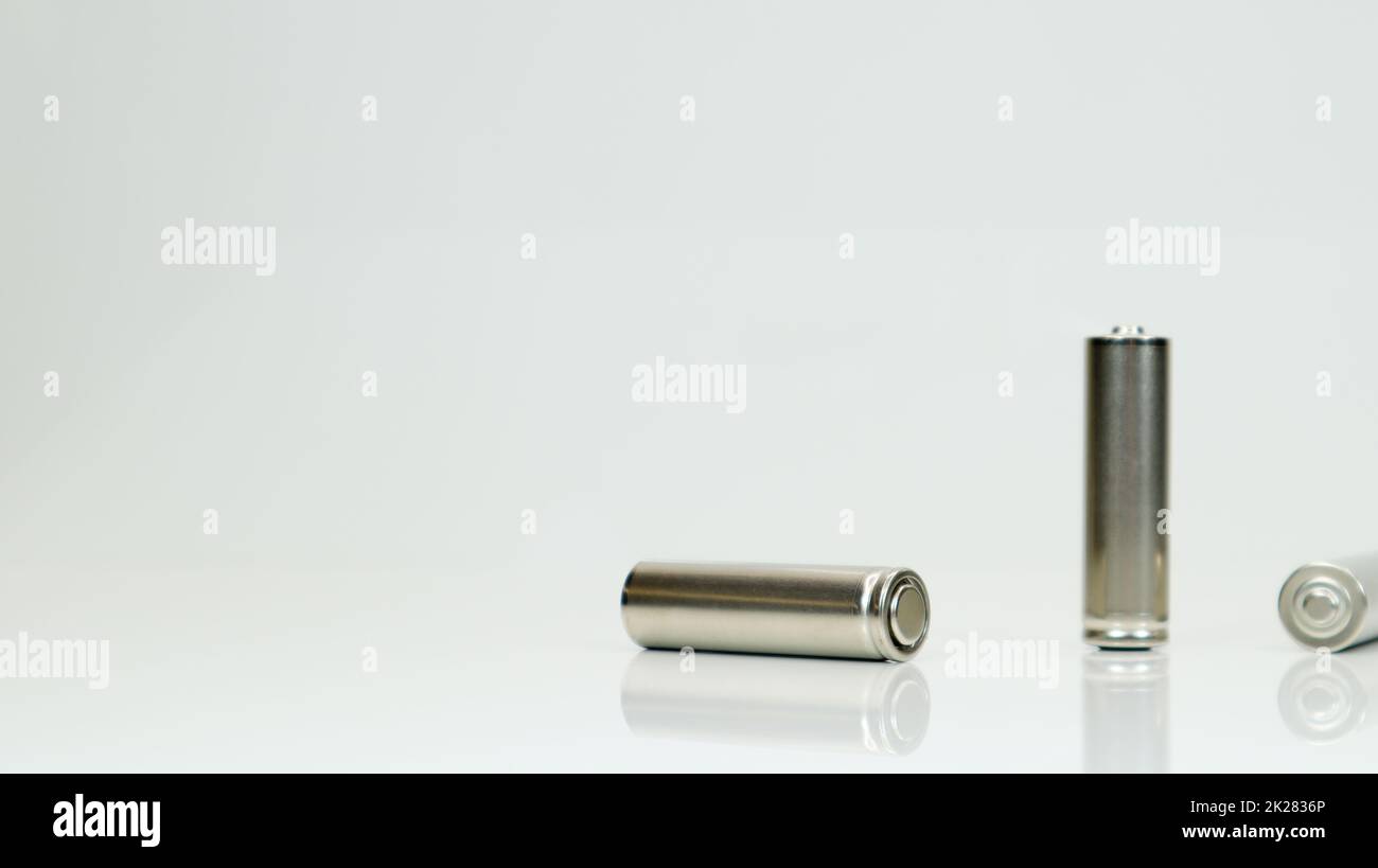 AA-Alkaline-Akkus auf weißem, glänzendem Hintergrund mit Reflexion. Schließen Sie drei leere Batterien mit Platz für Kopien. Stockfoto