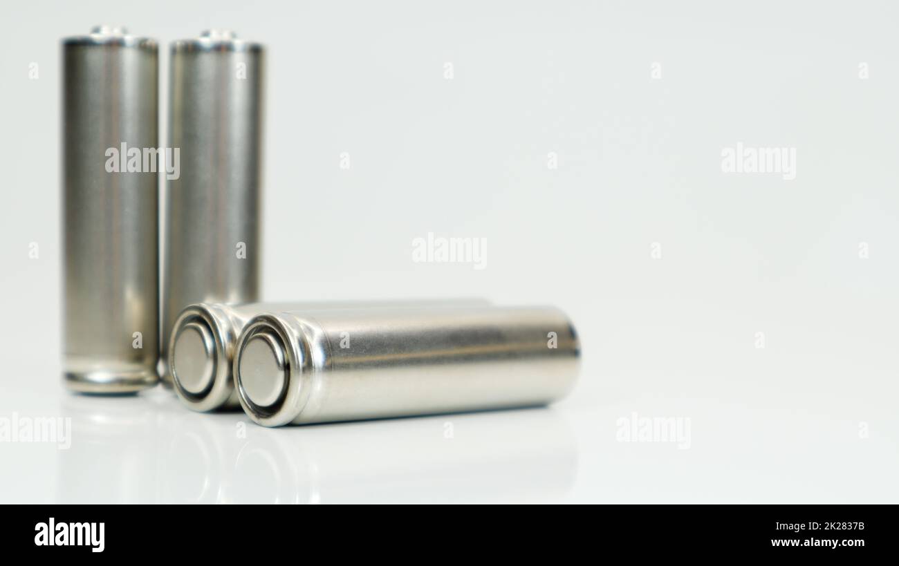 AA-Alkaline-Akkus auf weißem, glänzendem Hintergrund mit Reflexion. Vier leere Batterien mit Platz zum Kopieren. Stockfoto