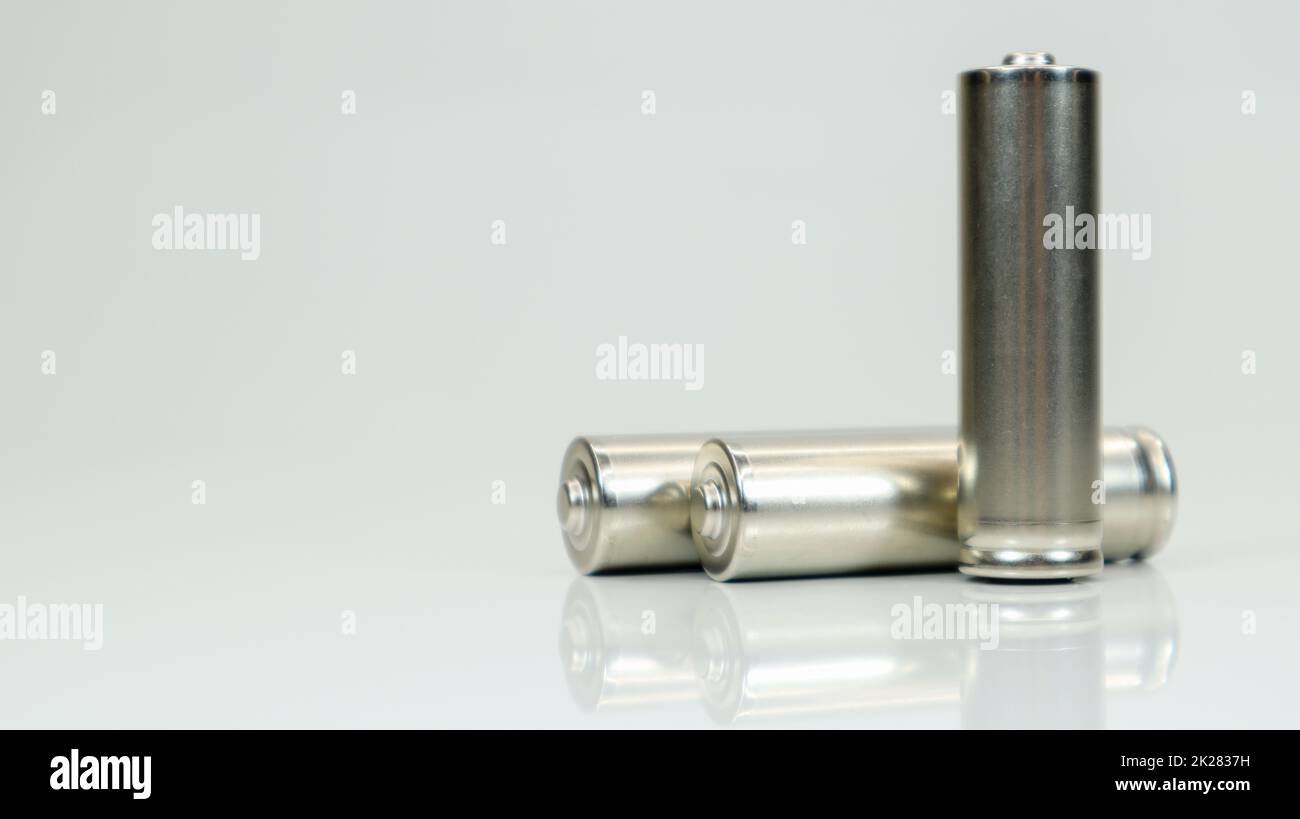 AA-Alkaline-Akkus auf weißem, glänzendem Hintergrund mit Reflexion. Schließen Sie drei leere Batterien mit Platz für Kopien. Stockfoto