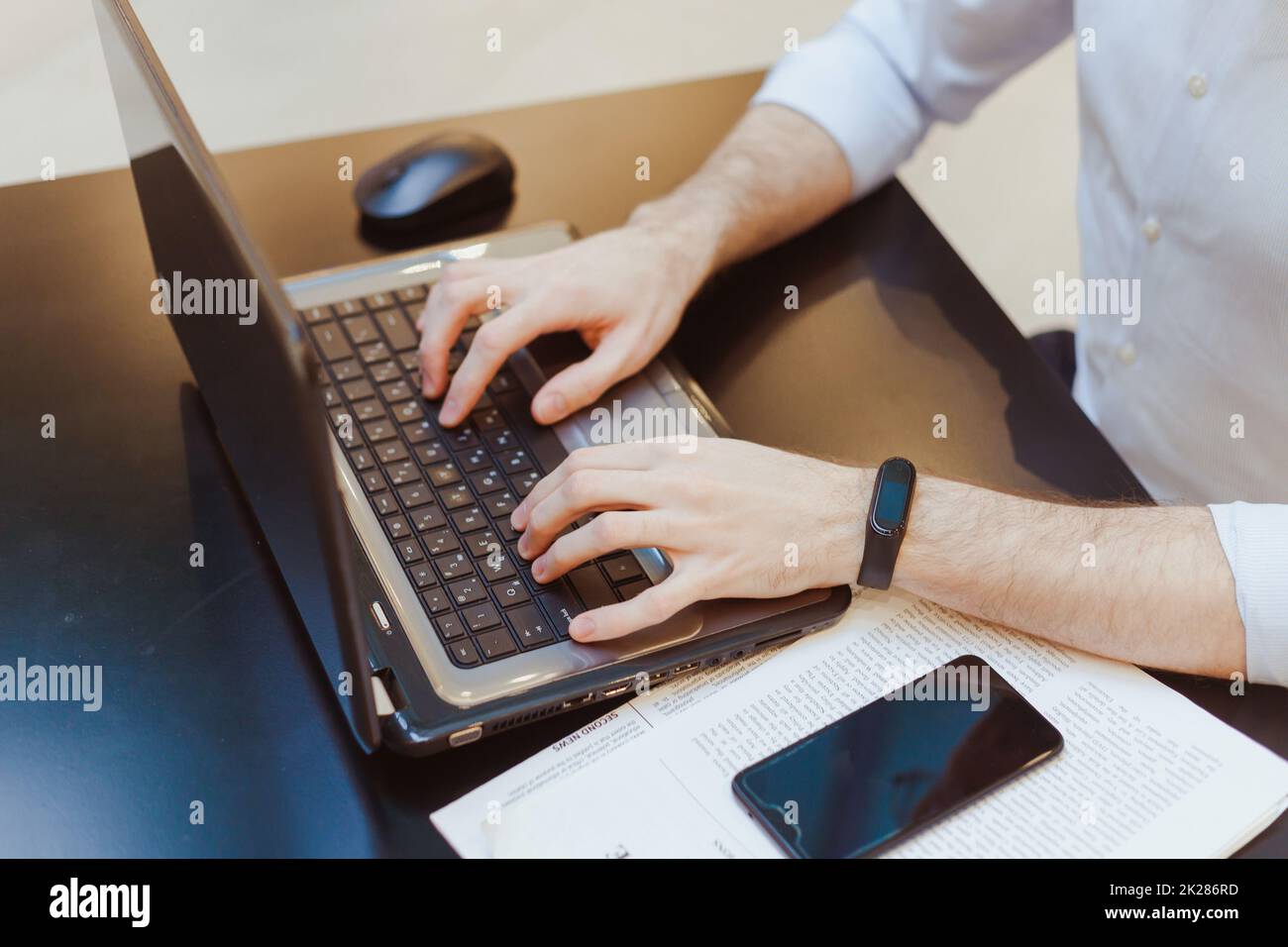 Handarbeit mit Laptop mit Papier, Smartphone und Maus auf dem Arbeitstisch Stockfoto