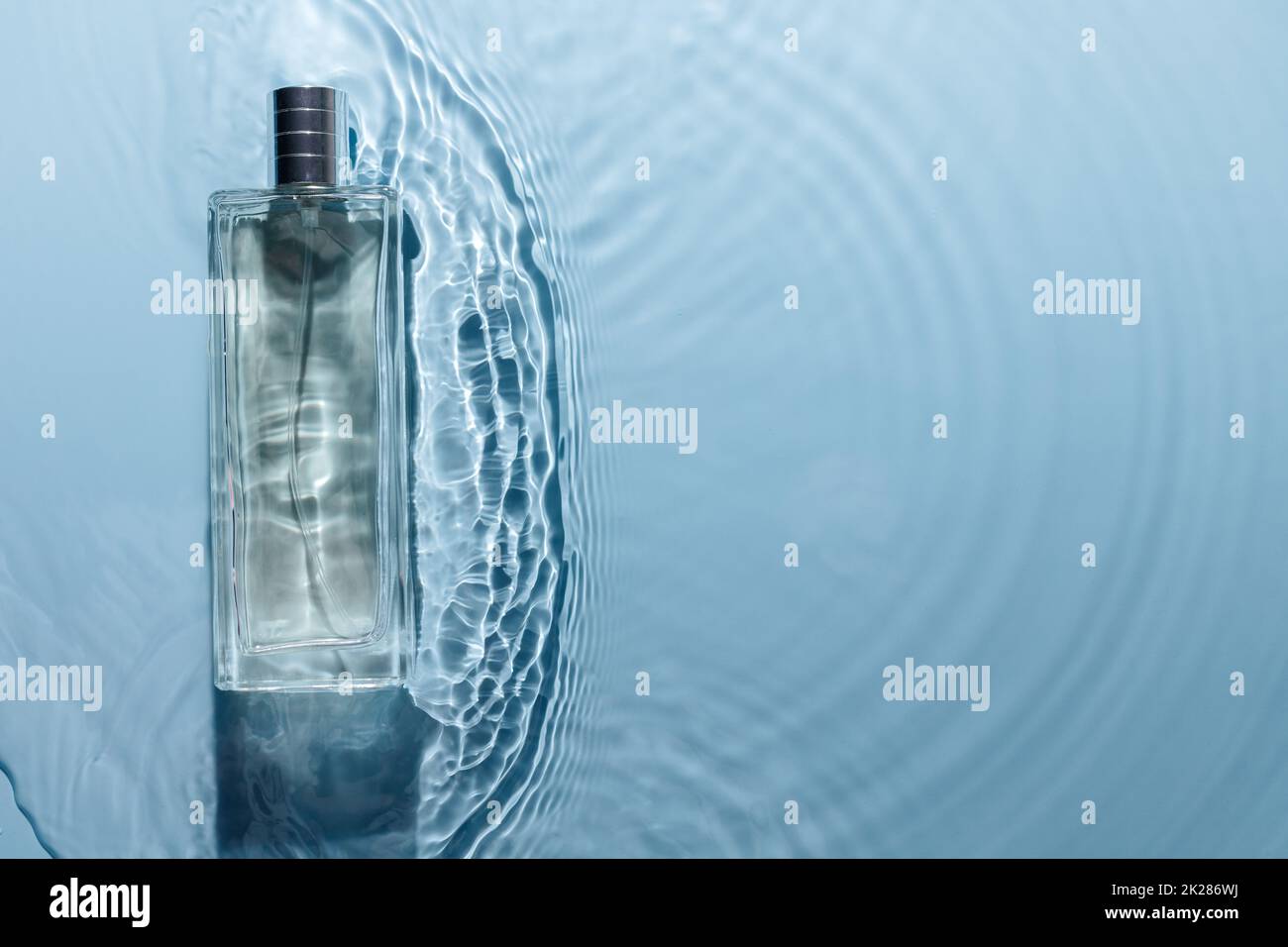 Parfümflasche auf blauem, welligem Hintergrund. Duftkonzept mit frischem Meeresduft. Rein Stockfoto