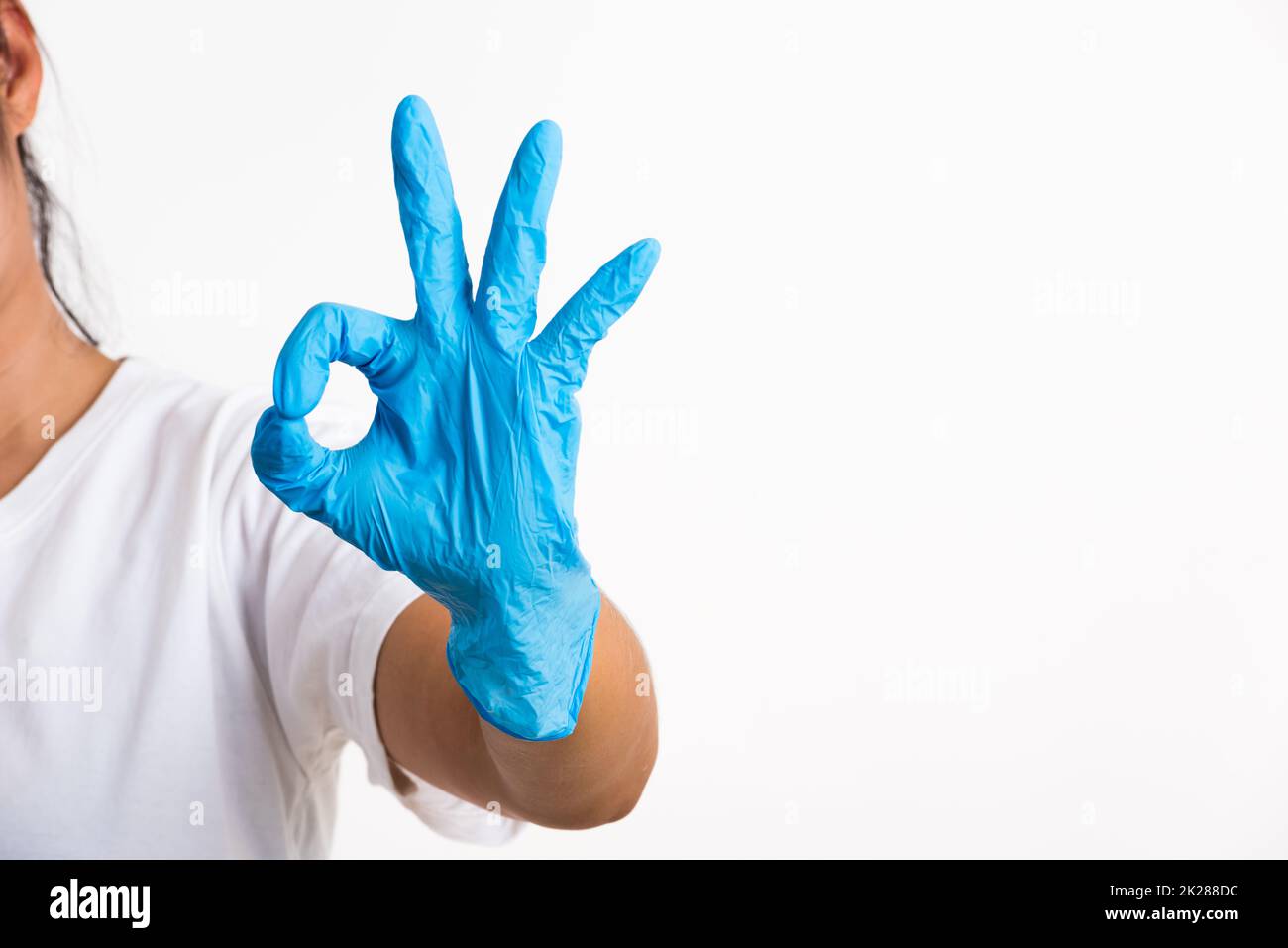 Frau trägt Hand zu blauem Gummihandschuh mit OK-Schild Stockfoto