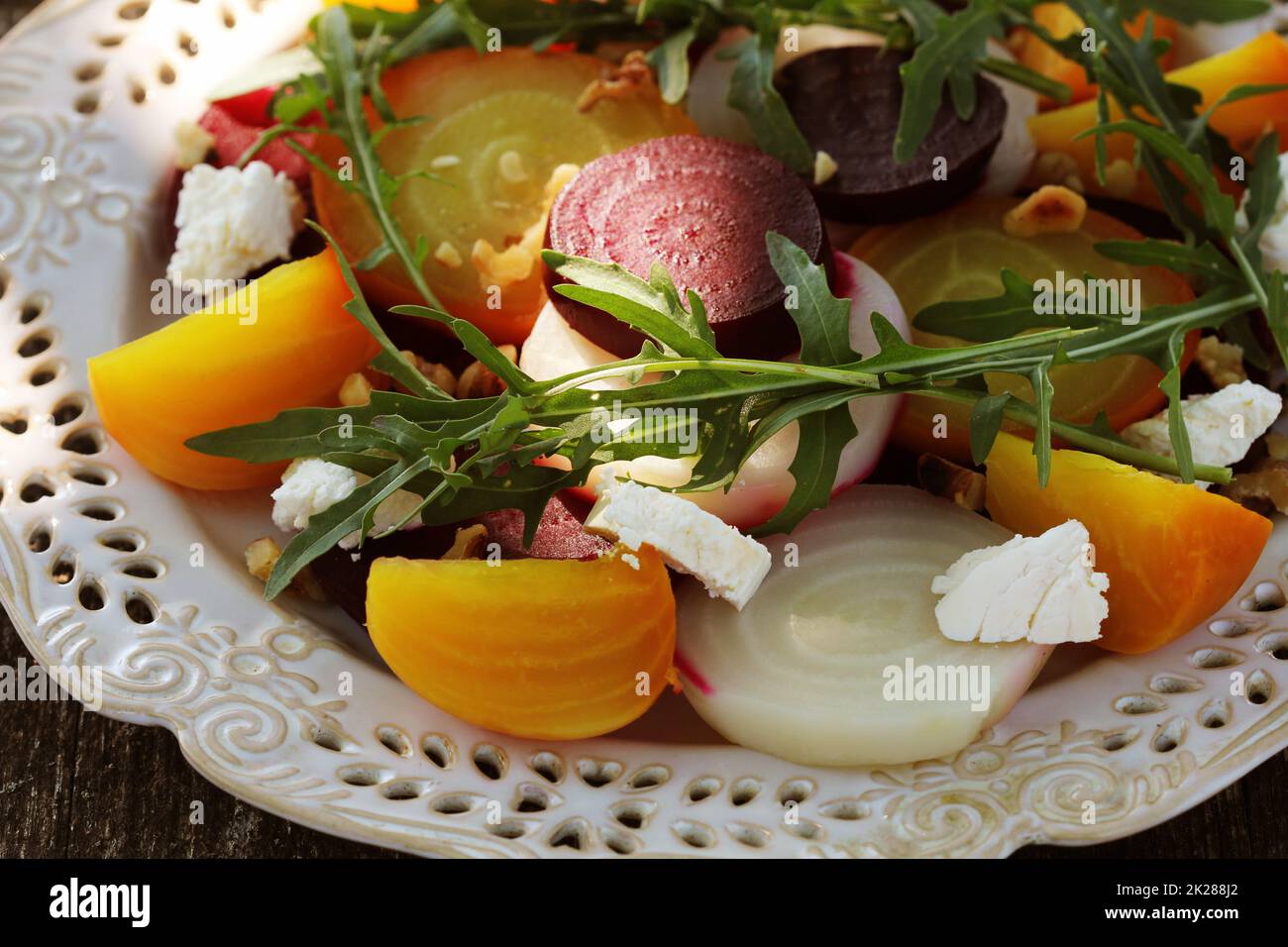 Gesunde Rüben Salat mit roten, weißen und goldenen Rüben, Rucola, Muttern, Feta Käse auf Holz- Hintergrund Stockfoto