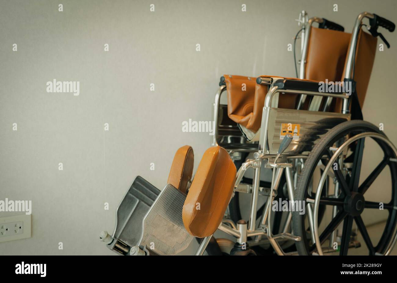 Leerer Rollstuhl in Wandnähe im Krankenhaus für Pflegebedürftige und Behinderte. Medizinische Hilfsmittel im Krankenhaus für alte Menschen. Rollstuhl für die Patientenversorgung im Pflegeheim. Stockfoto
