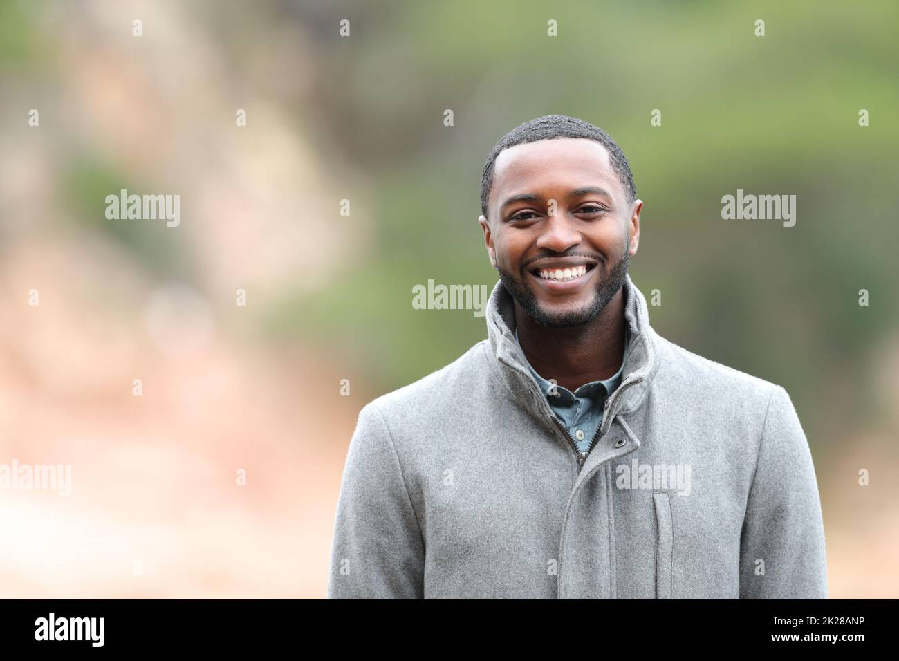 Glücklicher Mann mit schwarzer Haut sieht im Winter draußen in die Kamera Stockfoto