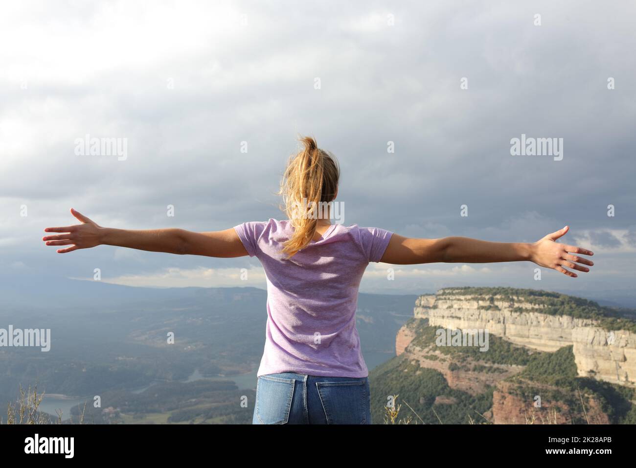 Eine Frau, die sich die Arme ausstreckt, um Urlaub in der Natur zu feiern Stockfoto