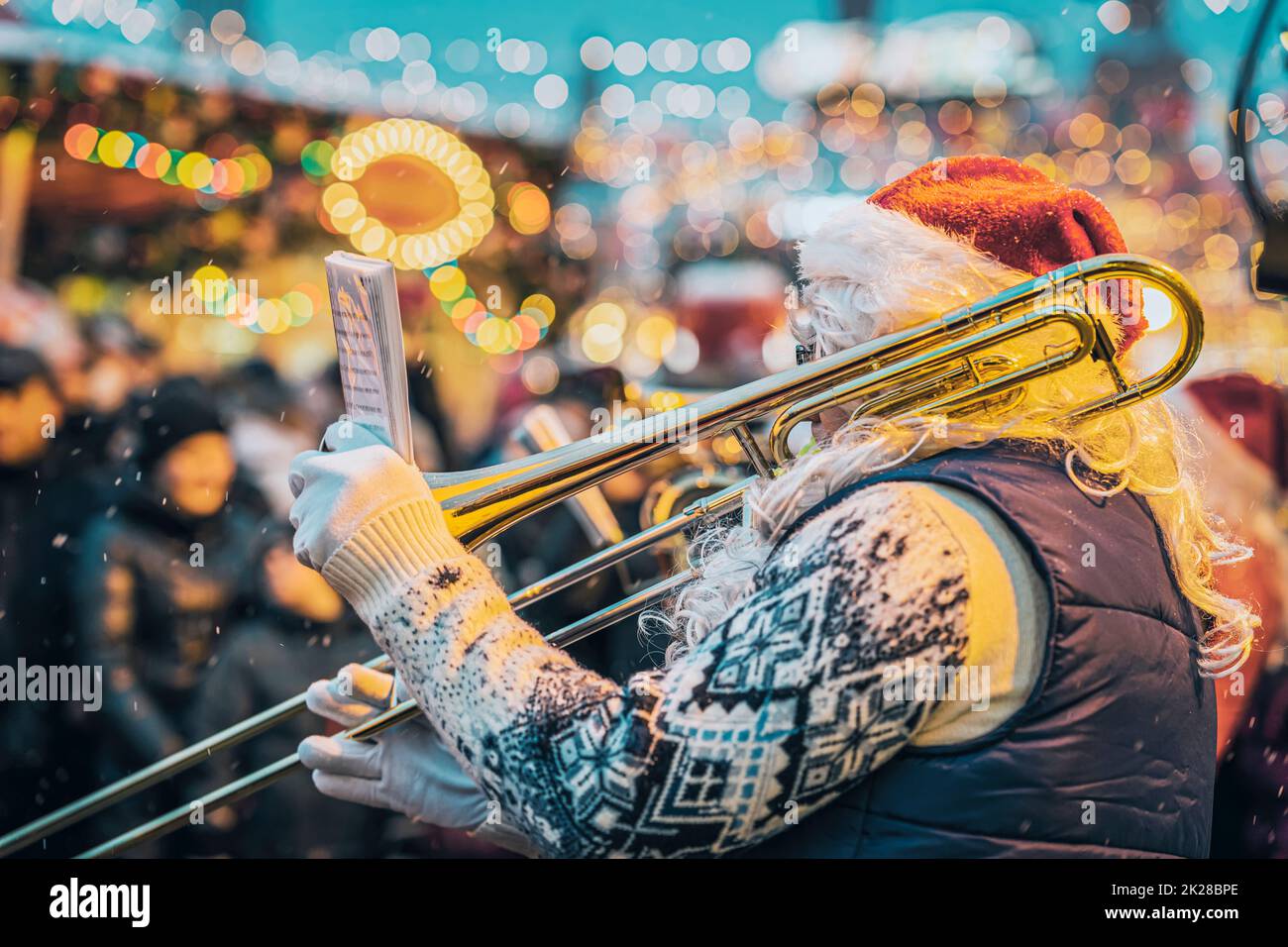 Jazzmusiker spielt Trompete im Weihnachtsmann Kostüm mit Notizbuch mit Noten. Weihnachtsstadtaufführung Stockfoto