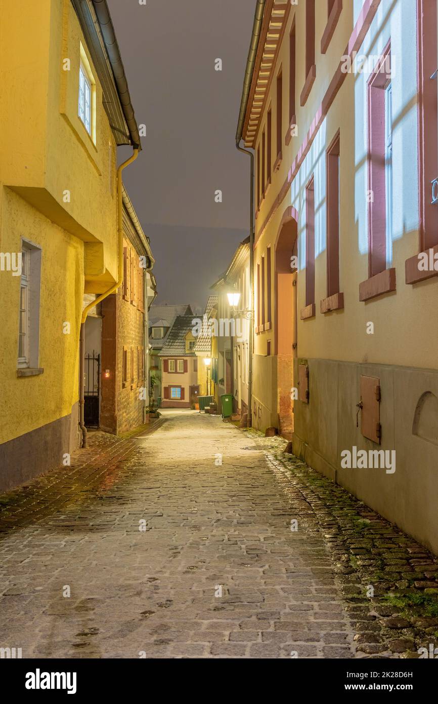 Beleuchtete kleine Gasse in einer kleinen deutschen Stadt in einer kalten Winternacht mit dünner Schneeschicht. Stockfoto