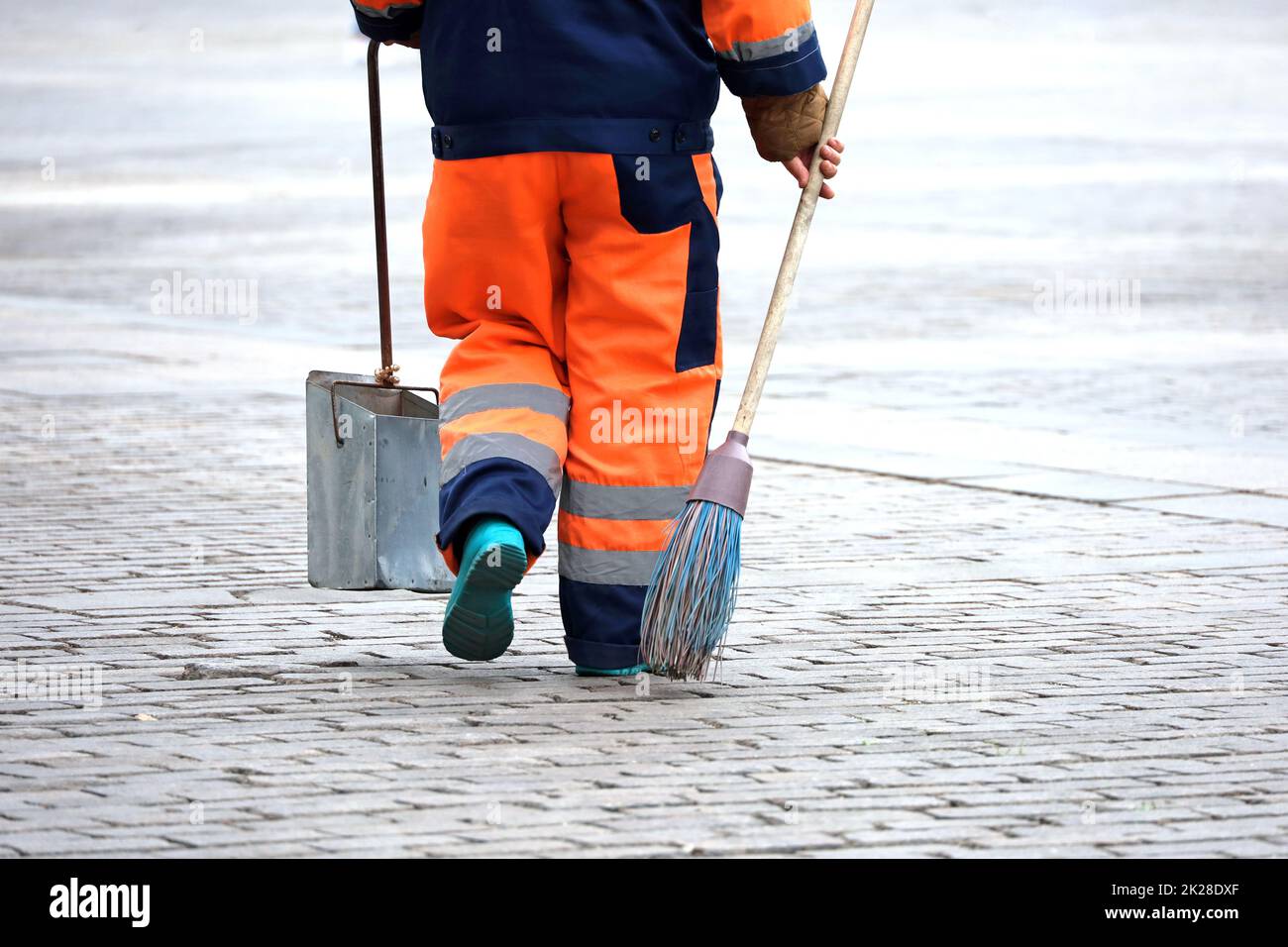 Hausmeisterin mit Besen und Schaufel auf einer Herbststraße. Reinigung der Stadt, Straßenkehrmaschine Stockfoto