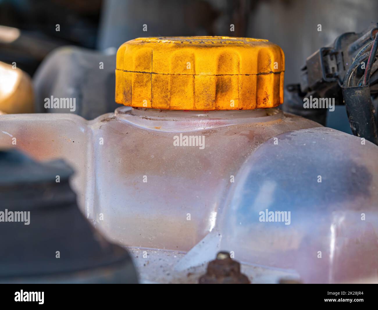 Kunststofftank mit gelbem Deckel für Frostschutzmittel des Motorkühlsystems. Stockfoto